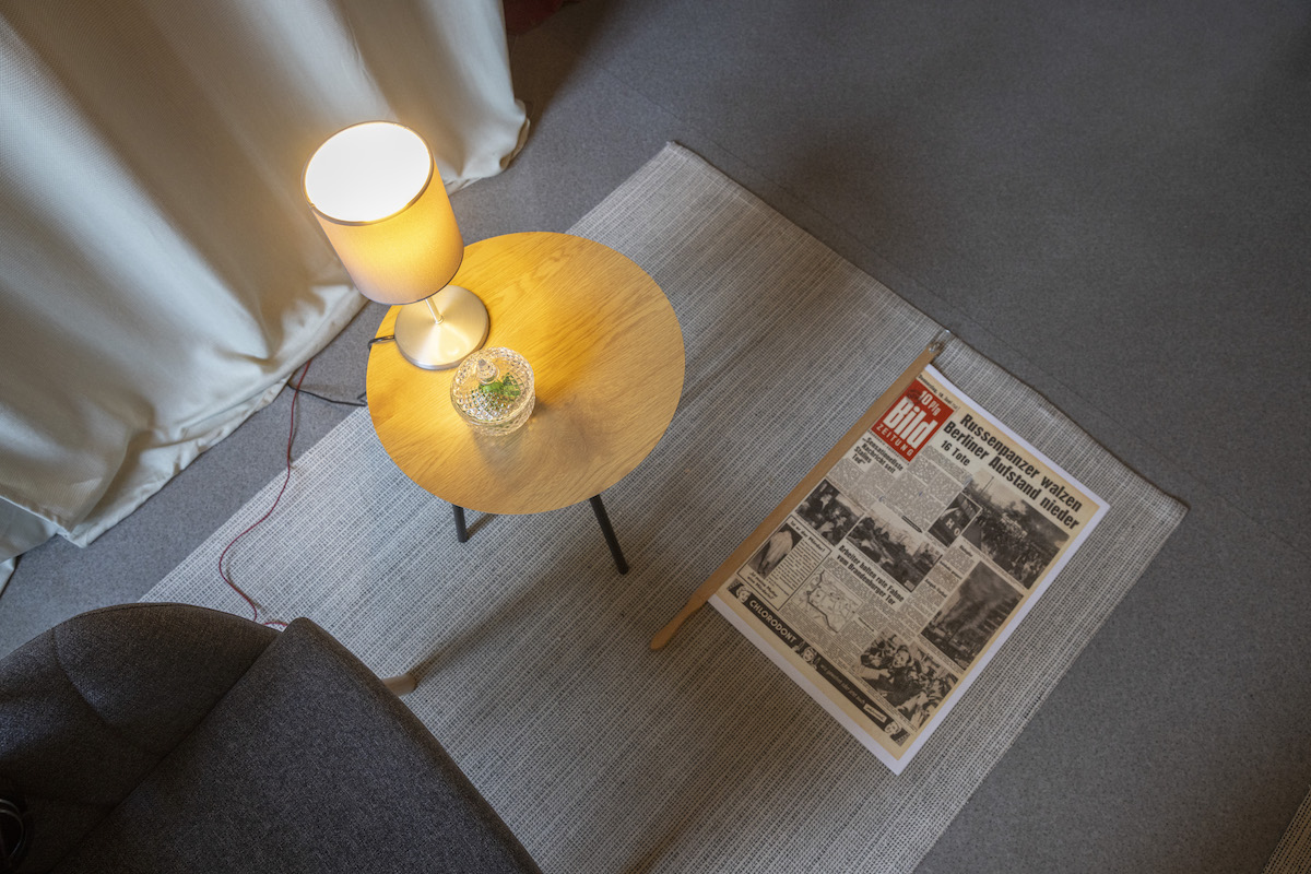 7F8A5761 Kopie Schreibtisch von oben mit Leselampe, Glas Wasser und historischer Zeitung zum 17. Juni 1953