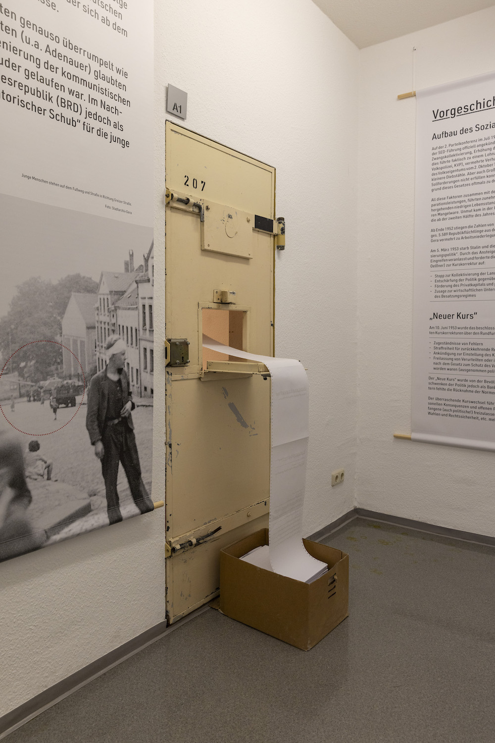 7F8A5778 Kopie Museumsausstellung mit beigefarbener Gefängnistür Nummer 207 vor historischen Wandtexten und Schwarzweißfotografien zum Volksaufstand 1953